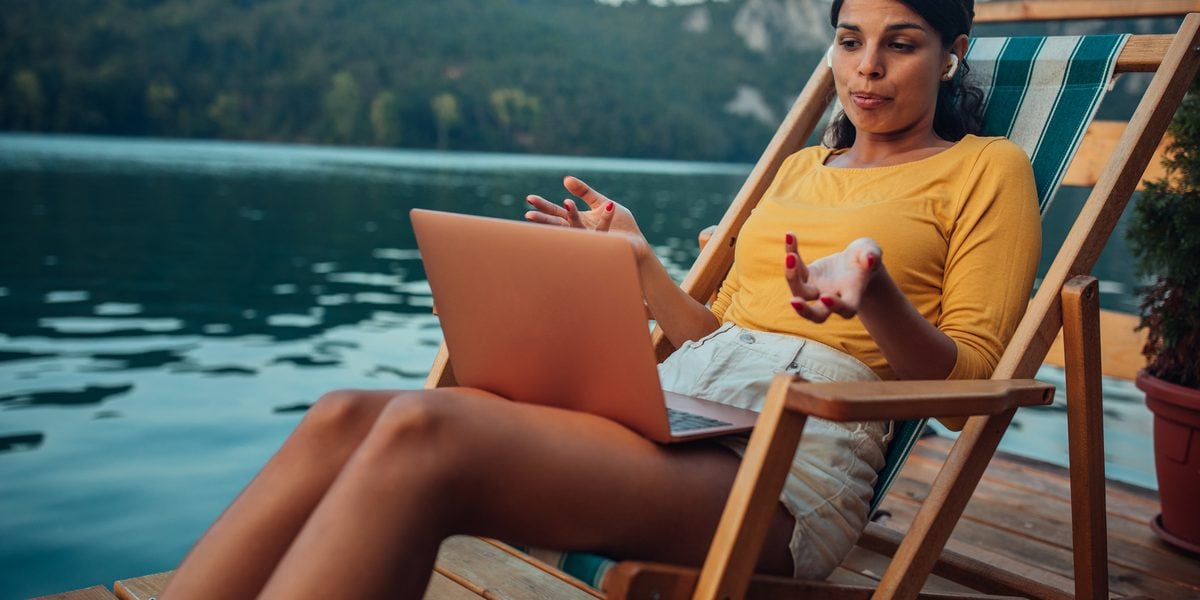 Profesional usando un portátil junto a un lago durante sus vacaciones