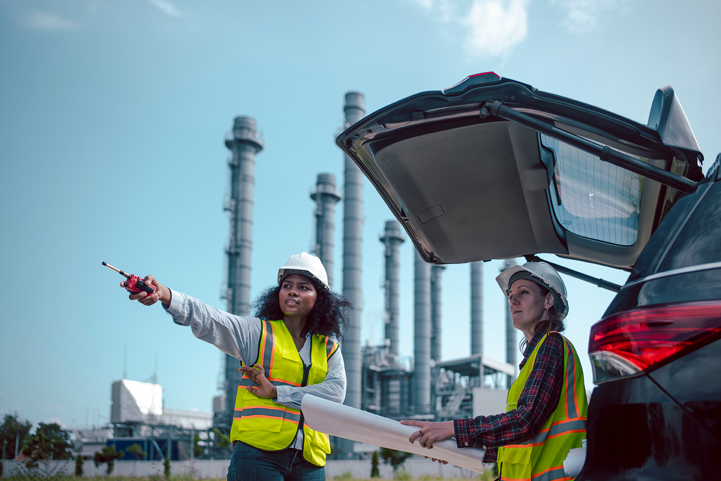 dos chicas trabajando en industria con cascos y chaleco amarillo
