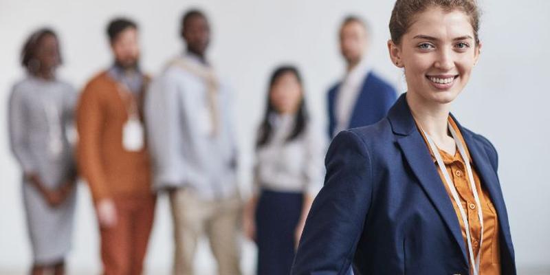 Mujer empresaria sonriendo con un equipo de trabajadores detrás