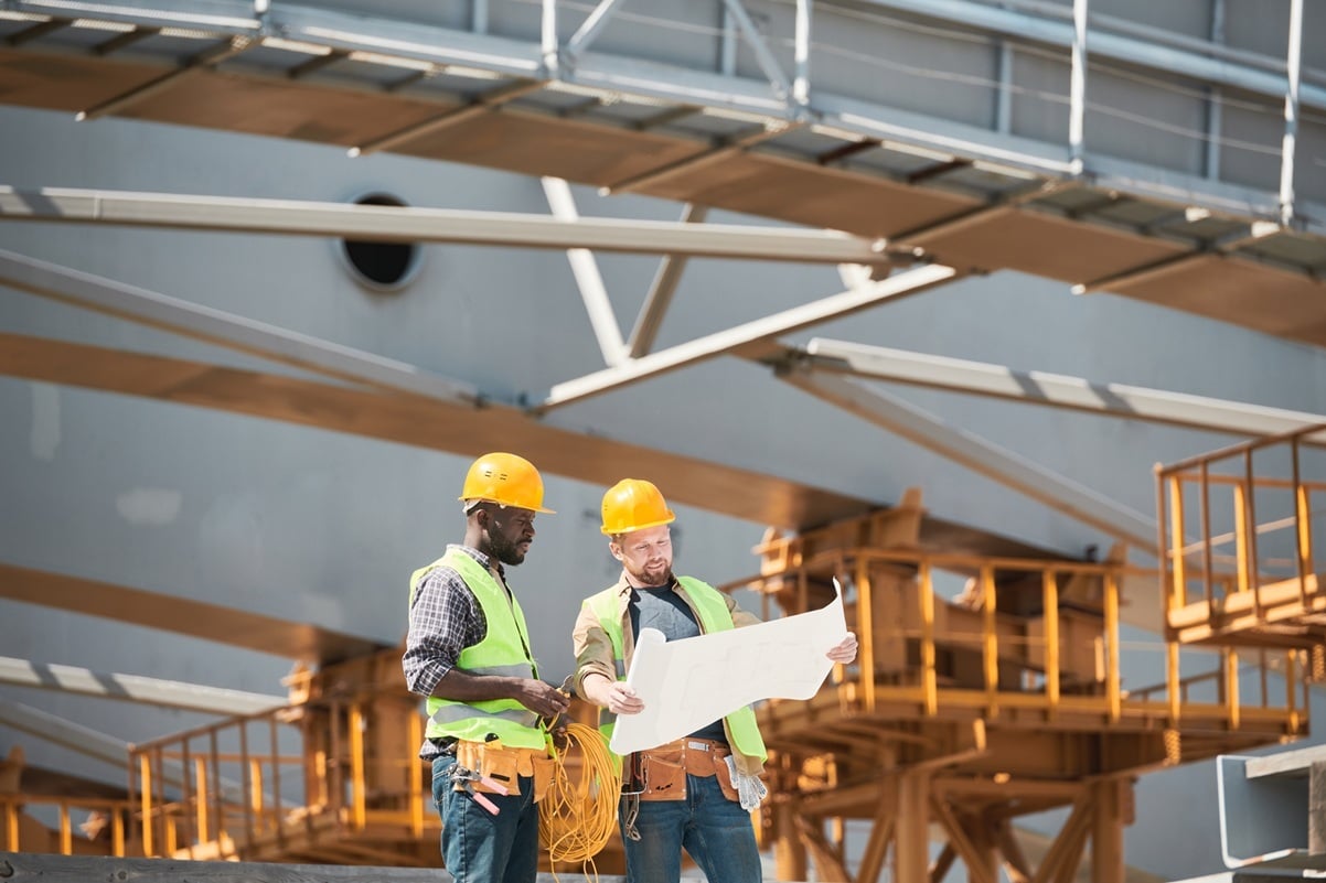 Dos hombres mirando un plano de construcción en un astillero